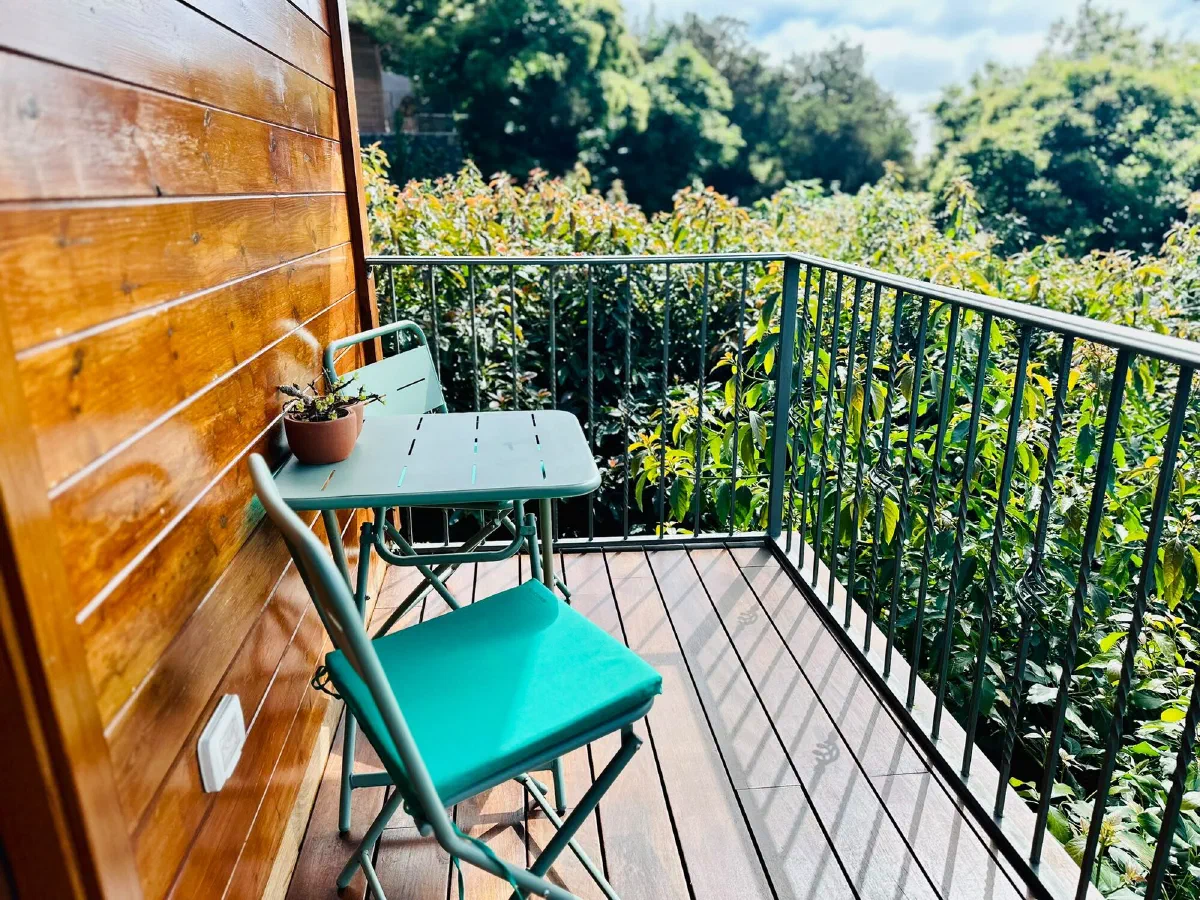 Cozy: balcony with a small teal table and chairs overlooking green trees