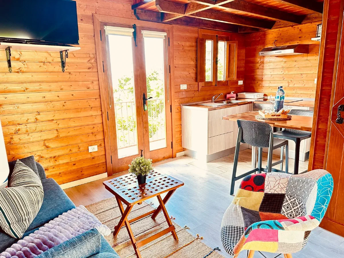 Cozy: wooden living area with sofa, open kitchen and glazed doors to the balcony
