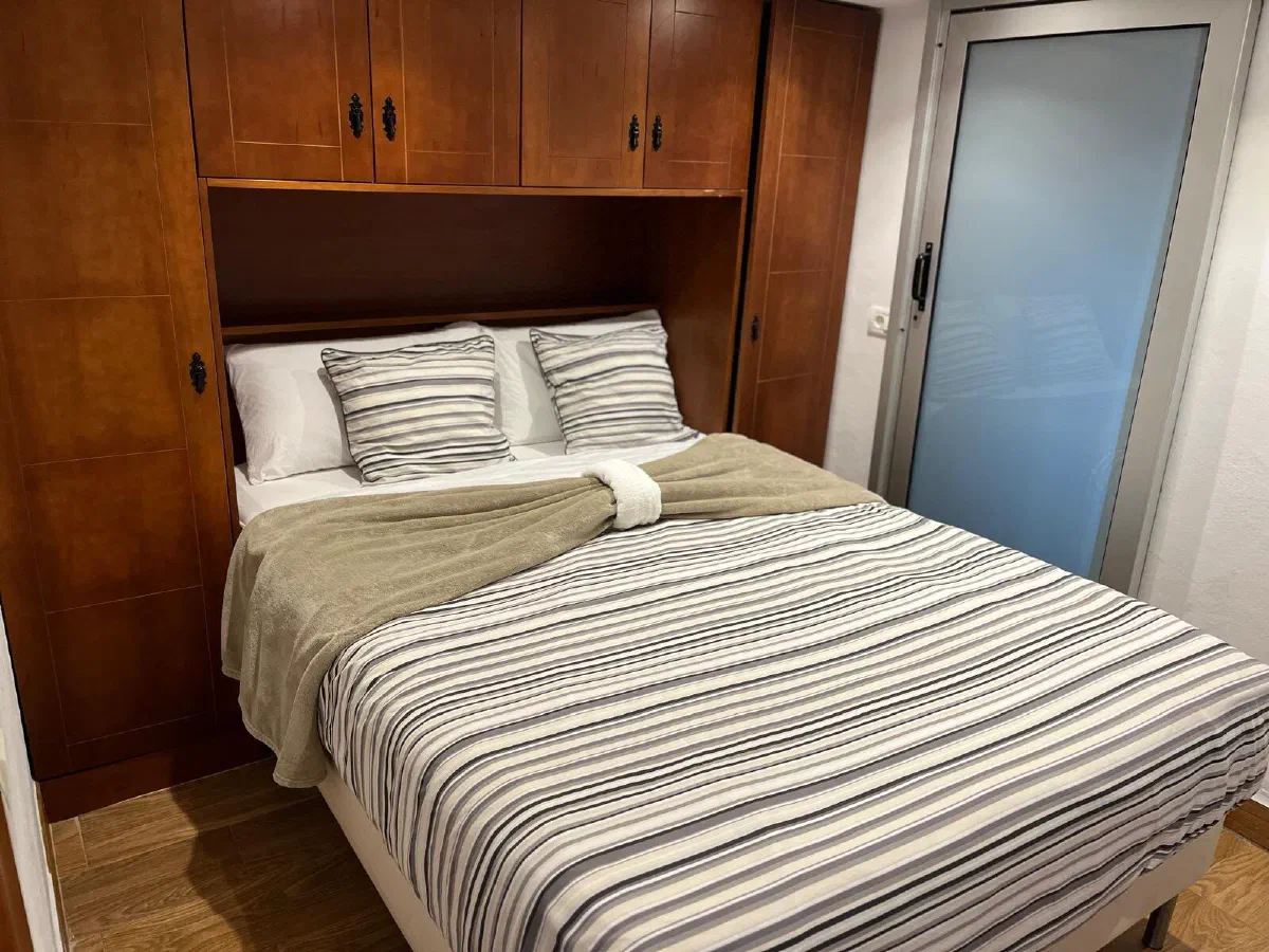 Encantadora: double bed with striped bedding and wooden wardrobes