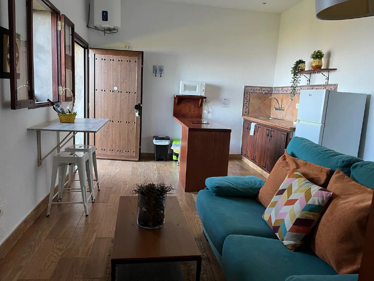 Encantadora: bright open-plan room with sofa, kitchen area and front door
