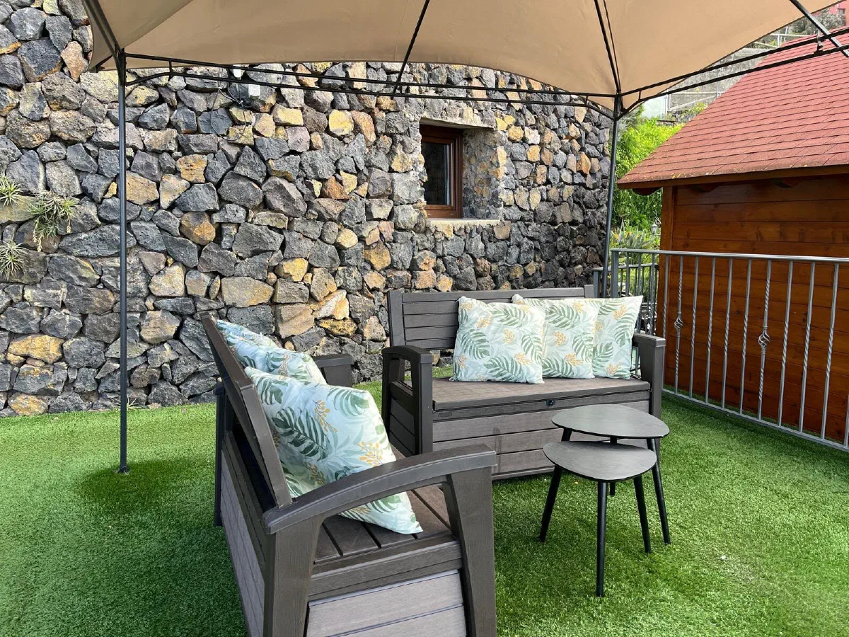 Encantadora: garden seating area under a gazebo, on artificial grass beside a stone wall