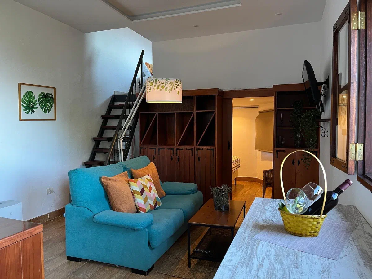 Encantadora: living room with a turquoise sofa, an open staircase and a wooden shelving unit