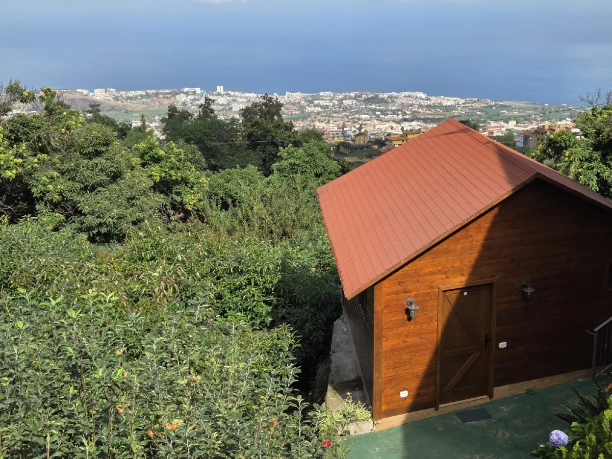 Wooden cabin with a red roof and a view over the valley and the coast